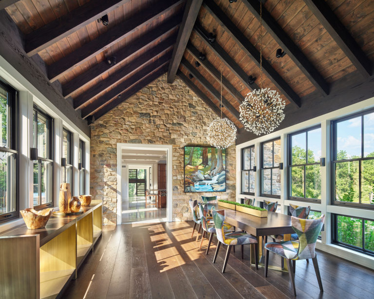 Contemporary dining room with vaulted ceiling, exposed beams and wood decking, stone wall and floor to ceiling windows