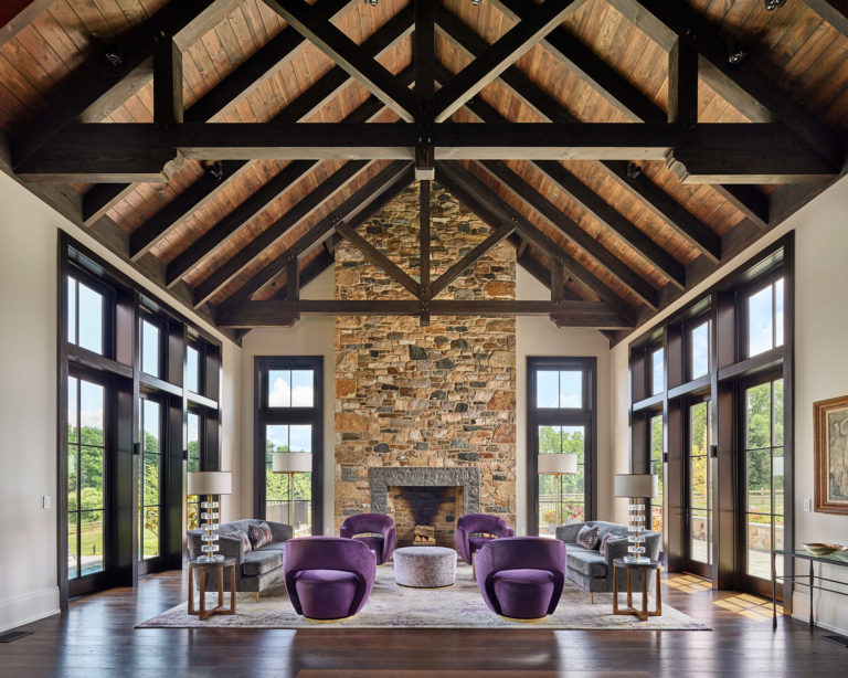 Contemporary great room with vaulted ceiling, exposed beams and wood decking, stone fireplace, hardwood floors and floor to ceiling windows