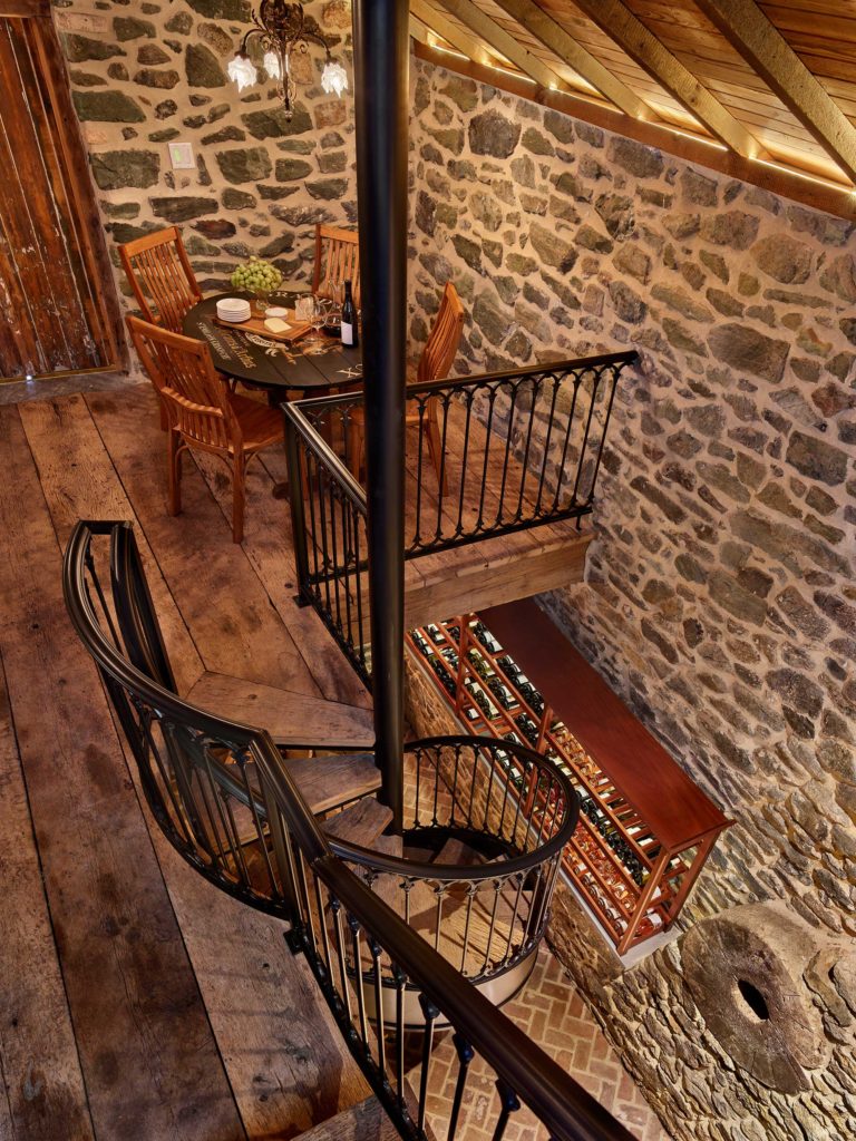 entertaining area with custom iron rail and spiral stair in wine cellar