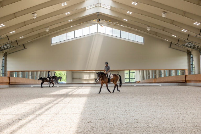 A person riding horses inside a building. This could have once been an office or a studio that an architect transformed into a country style site. Numerous projects may have a similar idea and environment, but the builder might proceed with construction and art very differently.