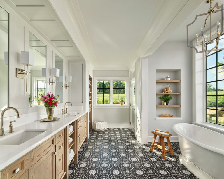 Master bathroom with white walls, patterned floor tile, soaking tub and black frame windows with views.