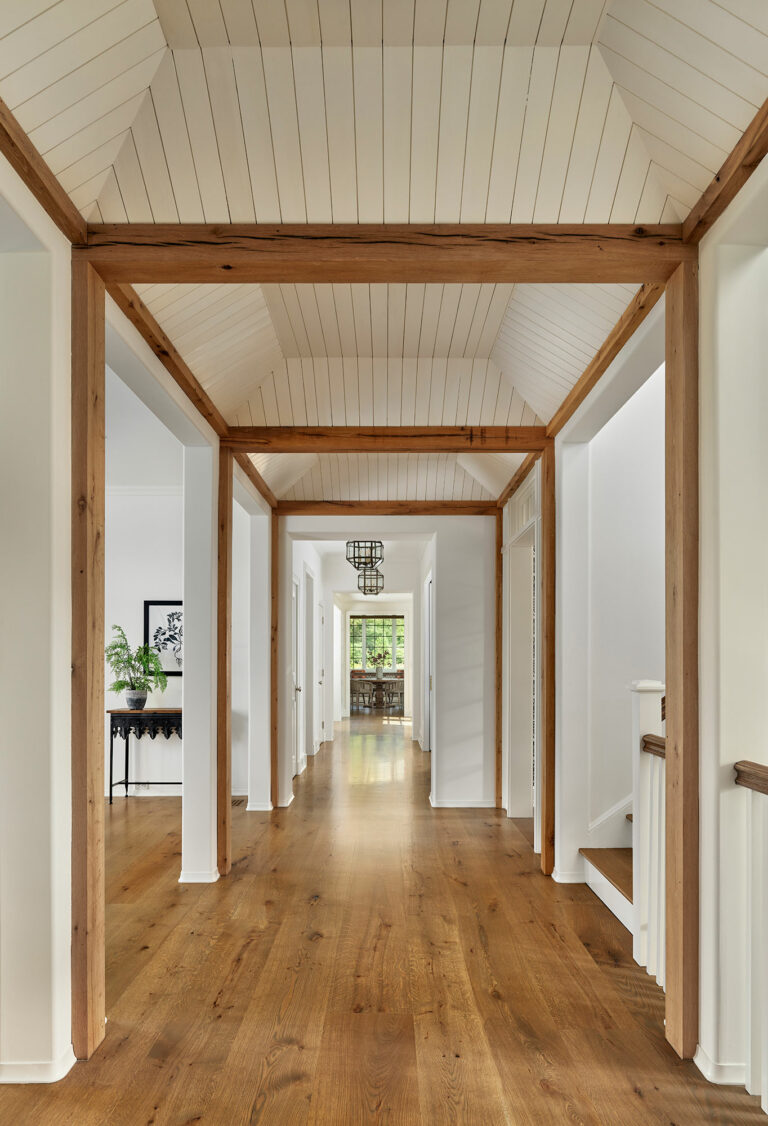 Hallway in Chestnut Fields, a contemporary farmhouse in Chester County with white walls and warm wood accents.