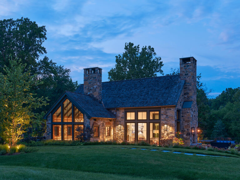 View into den and great room of new stone exterior farm house at dusk