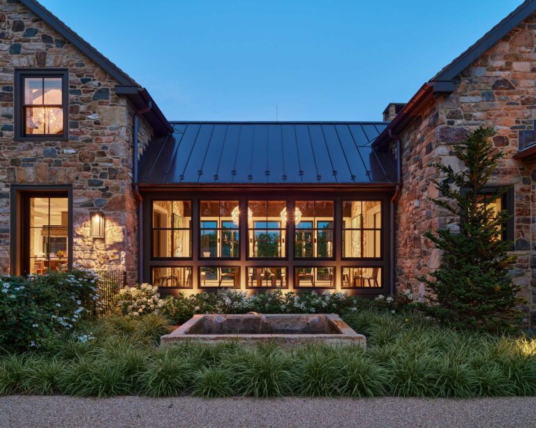 View into dining room from exterior of contemporary farm house at dusk