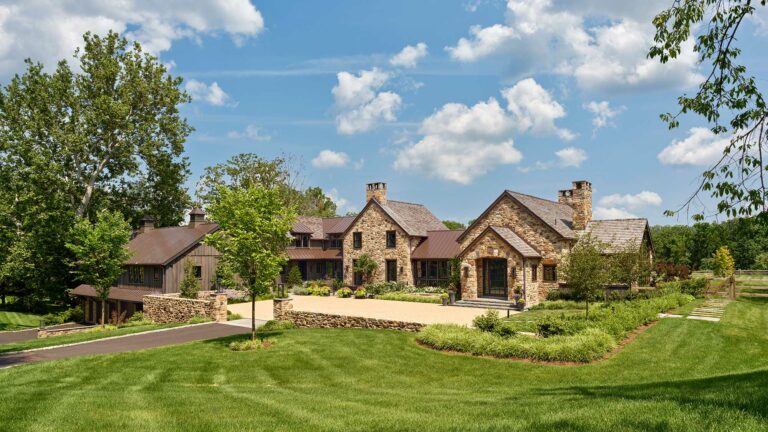 Auto court and entrance to stone and wood contemporary farm home with metal and cedar shake roof