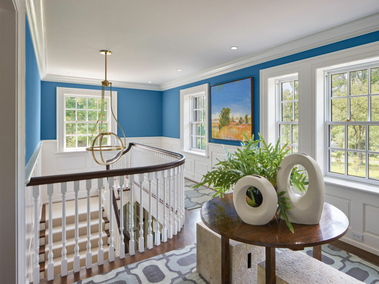 Upstairs stair hall with blue walls and white wainscot