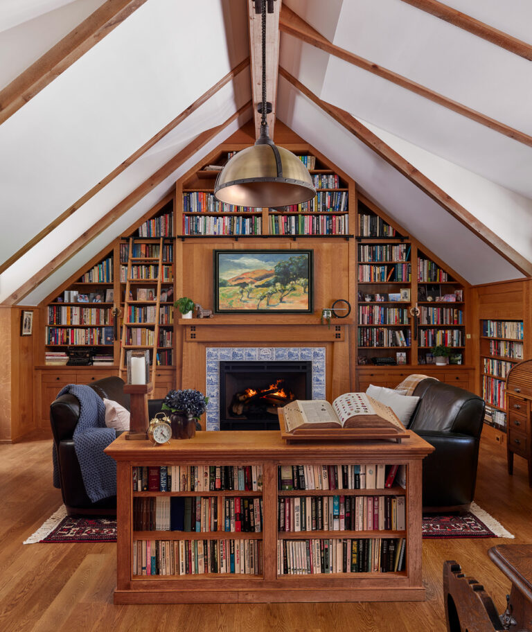 Custom wood shelving, mantel and fireplace surround with arts and crafts style detailing in a Gladwyne cottage library
