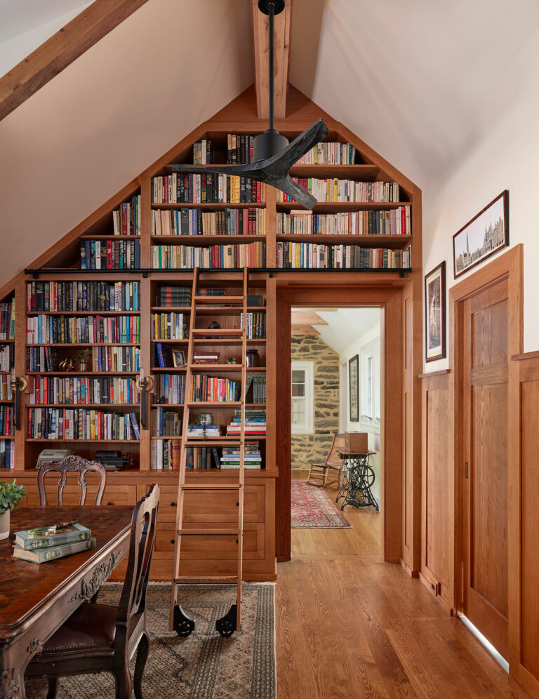 Custom wood shelving and sliding ladder in library in Gladwyne cottage
