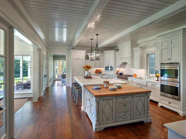 White kitchen with large island and hardwood floors with adjacent breakfast room at Evergreen Farm