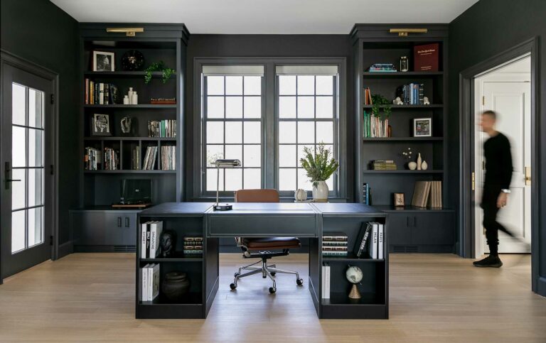 home office with dark walls, built in shelving and light wood floors