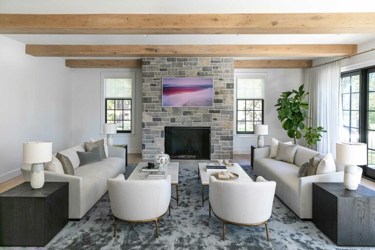 bright family room with exposed beams, stone fireplace, white walls and black frame windows and doors
