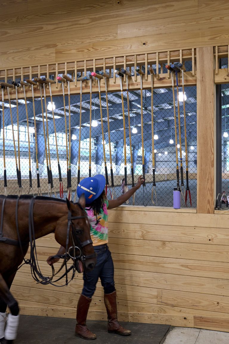 Young polo player choosing mallet at Chamounix Stables McCausland Arena for Work to Ride program